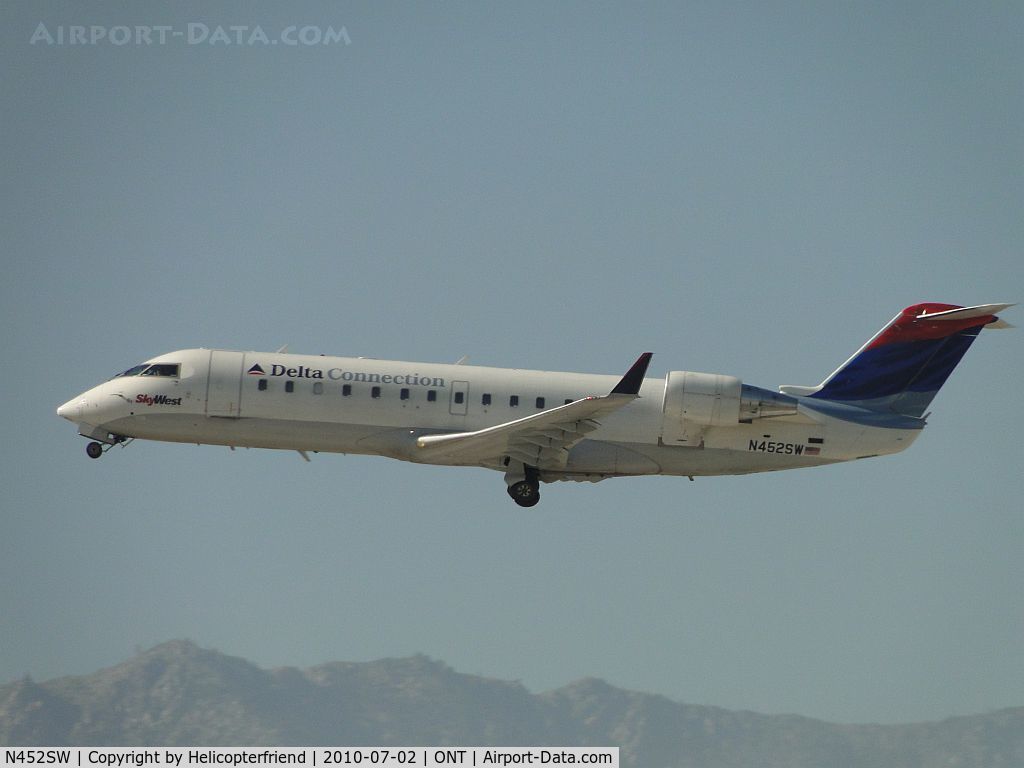 N452SW, 2002 Bombardier CRJ-200ER (CL-600-2B19) C/N 7716, Delta Connection by Sky West with wheels retracting after lift off from runway 26R and heading west