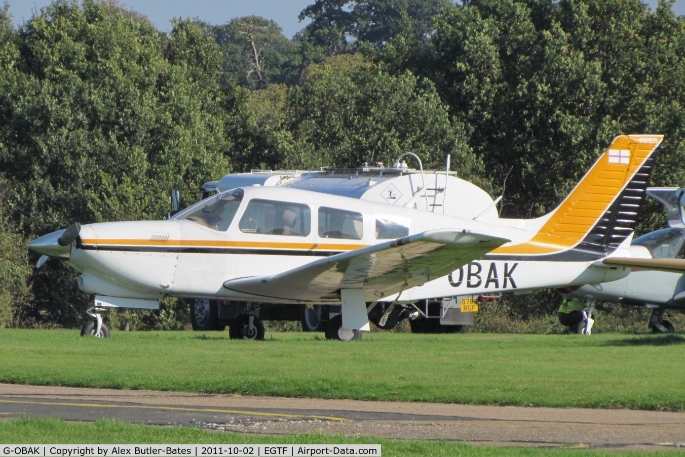 G-OBAK, 1977 Piper PA-28R-201T Cherokee Arrow III C/N 28R-7703054, Parked on the grass, in its now old colours.