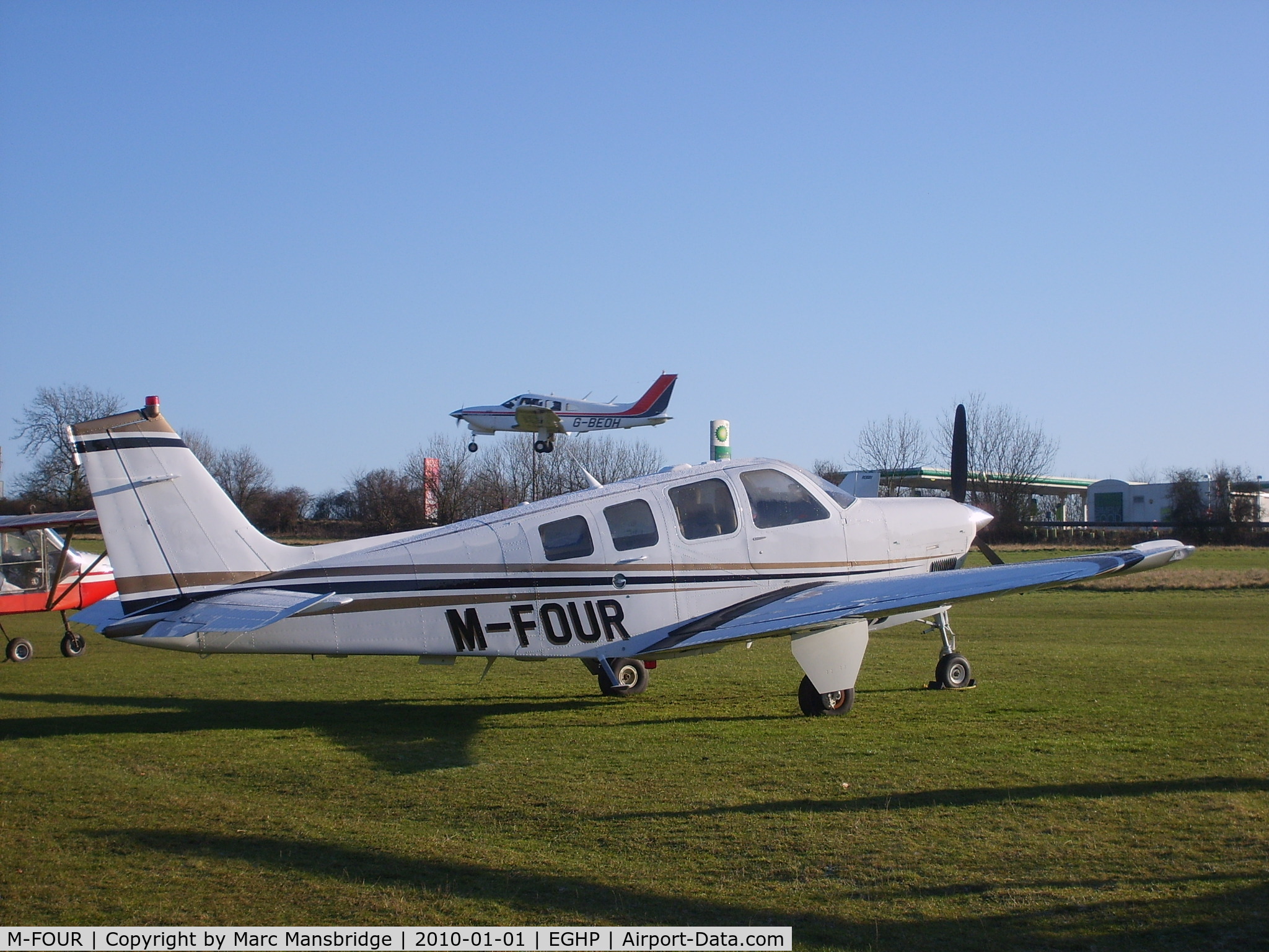 M-FOUR, 2008 Hawker Beechcraft G36 Bonanza C/N E-3849, Parked at Popham airfield EGHP with G-BEOH landing over the top