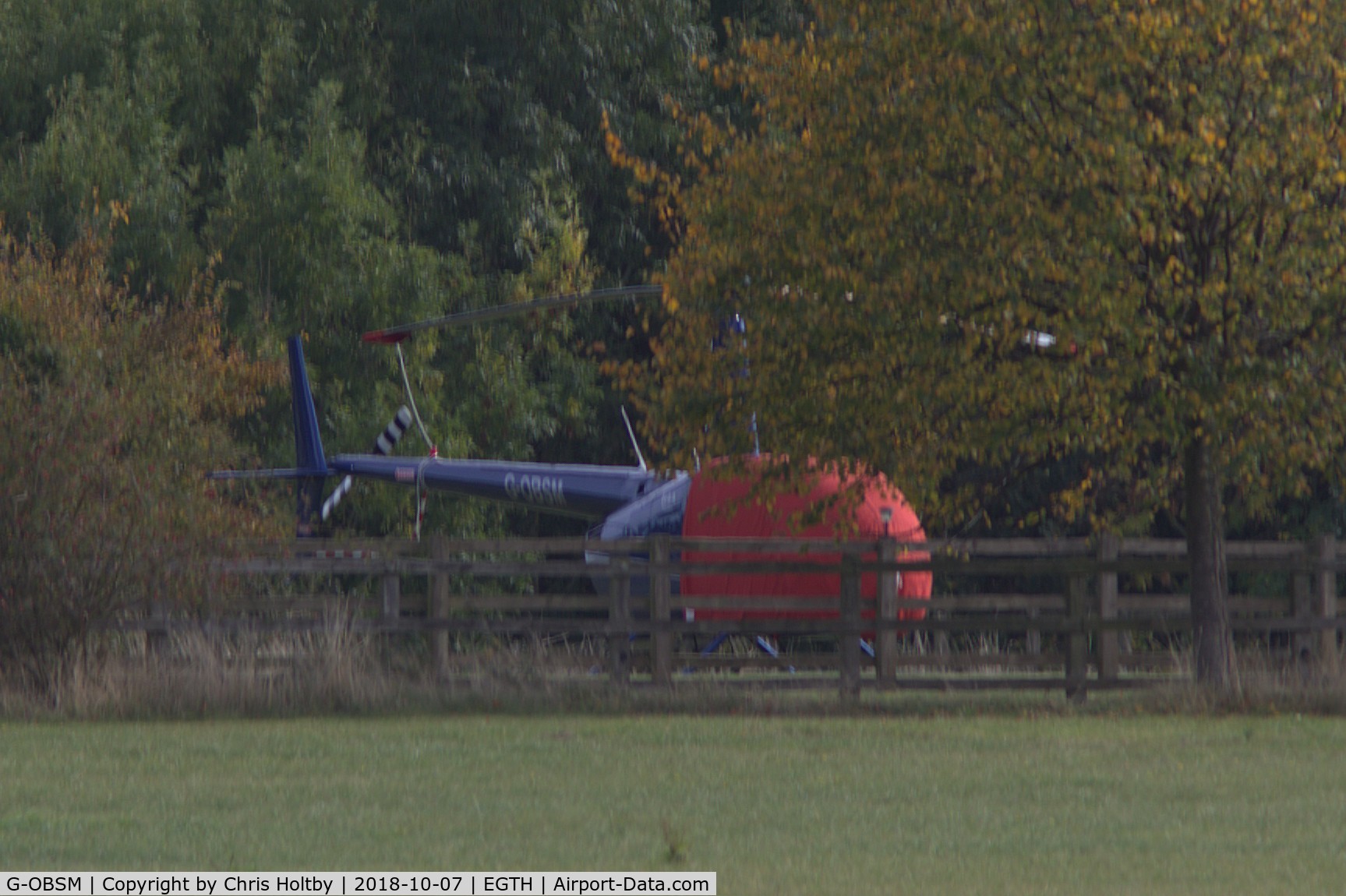 G-OBSM, 2001 Robinson R44 Raven C/N 1030, Parked and covered in private garden neighbouring Old Warden airfield on far side of main runway. Note change of livery.