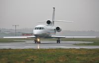 M-FALC @ EGHH - Taxiing to depart in pouring rain - by John Coates