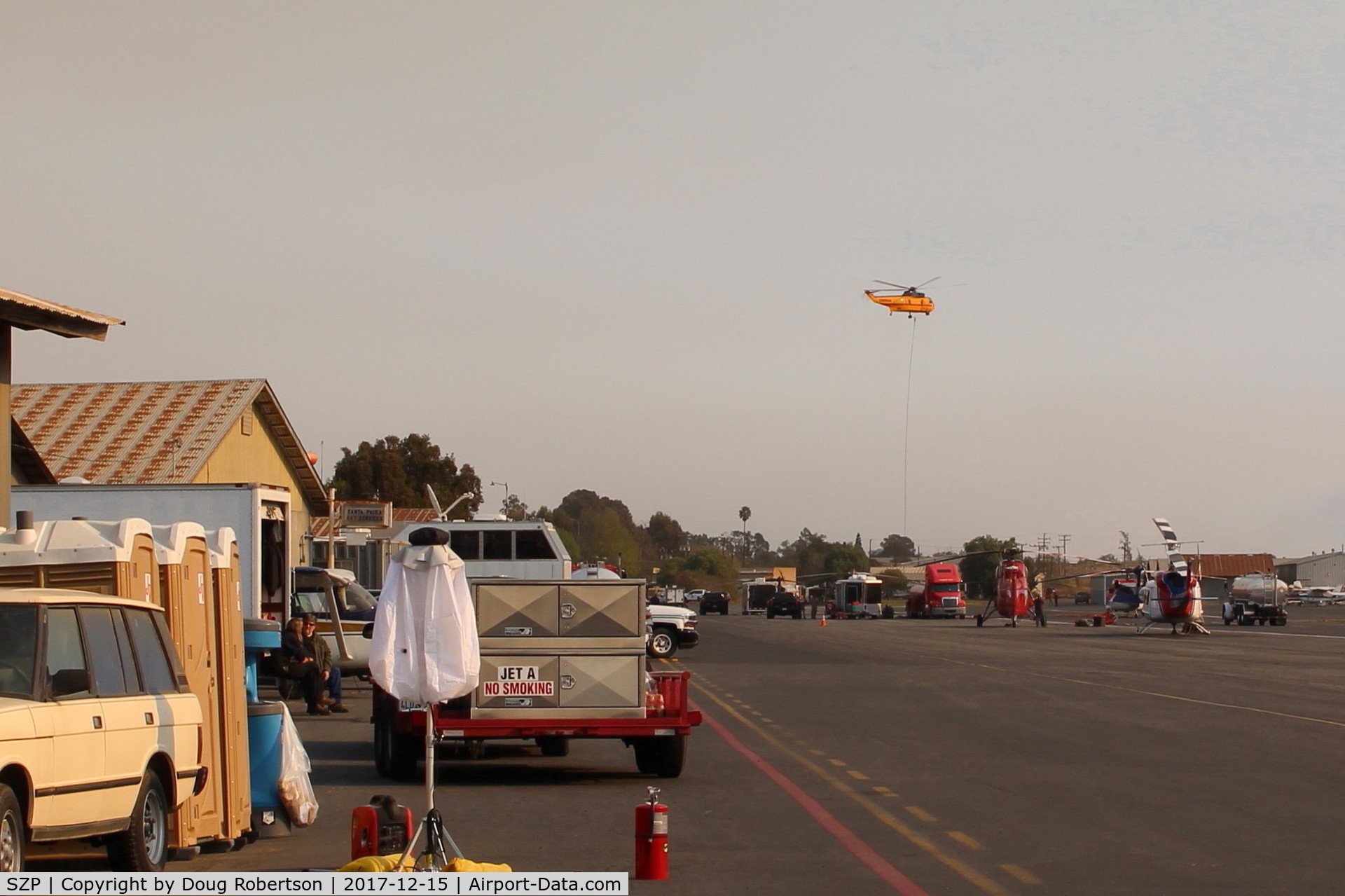 Santa Paula Airport (SZP) - CROMAN helicopter on departure to the Thomas Fire from SZP FireBase. Note PHOS-CHEK sling load and smoky sky.