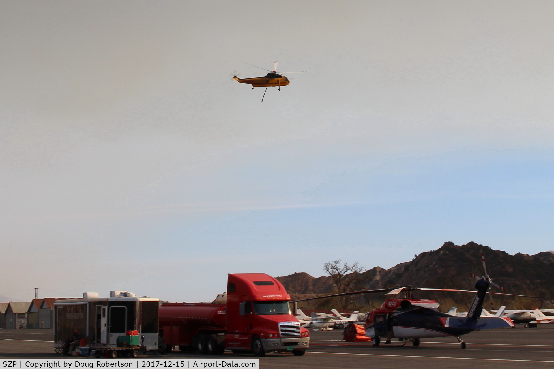 Santa Paula Airport (SZP) - CROMAN helicopter with Phos-Chek sling load dumped, returning to SZP Firebase. Note smoky sky.