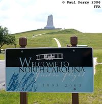 First Flight Airport (FFA) - The welcome sign at FFA, with the Wright Brother's Memorial in the background - by Paul Perry