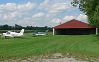 Trinca Airport (13N) - Two small planes sit on the apron by the hangar; the grass strip is in the background. - by Daniel L. Berek