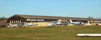 Fairoaks Airport - PART OF THE AIRCRAFT PARK WITH THE ALAN MANN HANGERS IN THE BACK GROUND - by BIKE PILOT