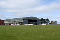 RAF Syerston Airport, Newark-on-Trent, England United Kingdom (EGXY) - Overview of the Air Cadets flightline. The old 1939 built J-type hangar is still in use, but the watchtower to the right is now replaced by a mobile caravan. - by Joop de Groot