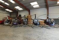 Wellesbourne Mountford Airfield - from L to R G-JHEW, G-RUZZ, G-OSAZ, G-BMIZ and G-ZAPY inside the Heli Air hangar - by Chris Hall