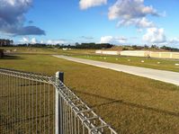 North Shore Aerodrome Airport, Auckland New Zealand (NZNE) - View from public car park down runway. Private hangars on far side. - by magnaman