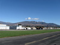 Santa Paula Airport (SZP) - Newer and older hangars. Santa Paula Peak at 4,957' in center right background. Hines Peak at 6,704' of Topa Topa Mountains beyond saddle barely shows near left side. - by Doug Robertson