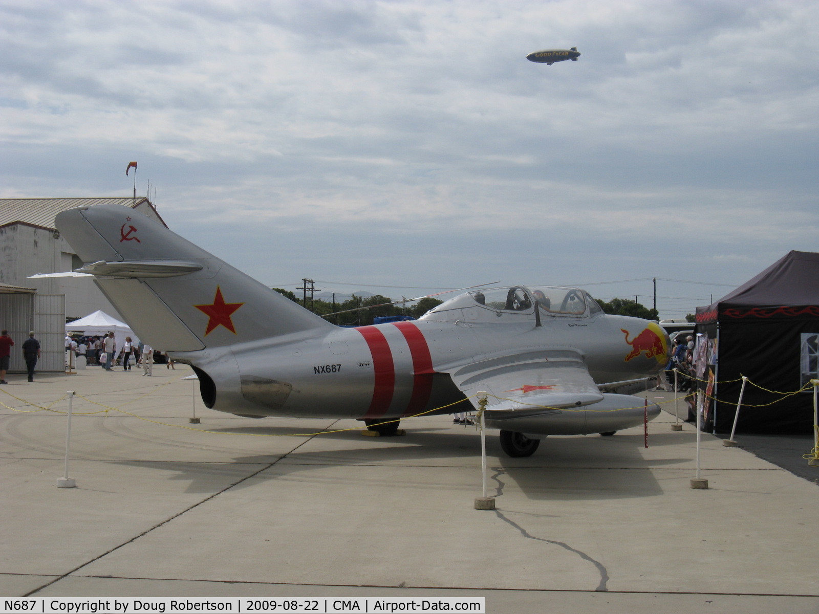 N687, 1953 Mikoyan-Gurevich MiG-15UTI C/N 1A02005, 1953 Mikoyan Gurevich MIG 15UTI tandem trainer 'Red Bull', Klimov VK-1A 5,952 lb st afterburning turbojet. NATO code name Midget. N10A Goodyear 'Spirit of America' Blimp in background sky.