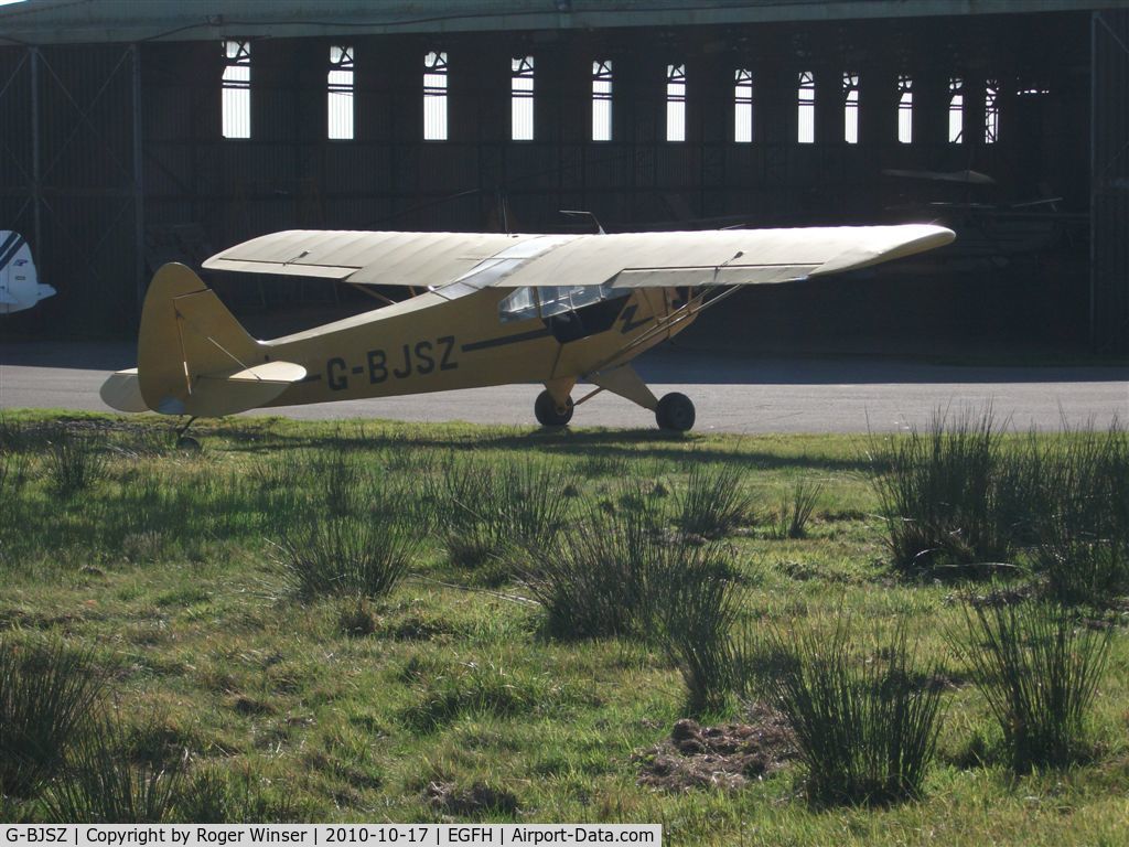 G-BJSZ, 1944 Piper L-4H Grasshopper (J3C-65D) C/N 11874, Through the fence. Classic Piper Cub basking in the morning sun.