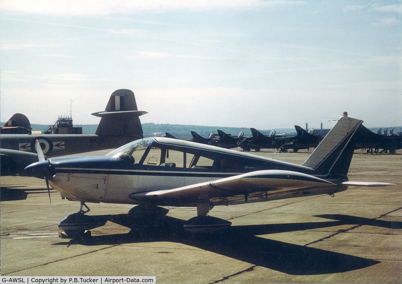 G-AWSL, 1968 Piper PA-28-180 Cherokee C/N 28-4907, G-AWSL parked on the apron at RAF Chivenor, North Devon, UK, next to Meteors and Hunters, while on a visit from its home airfield of Fairoaks, Surrey. 1974 approx.