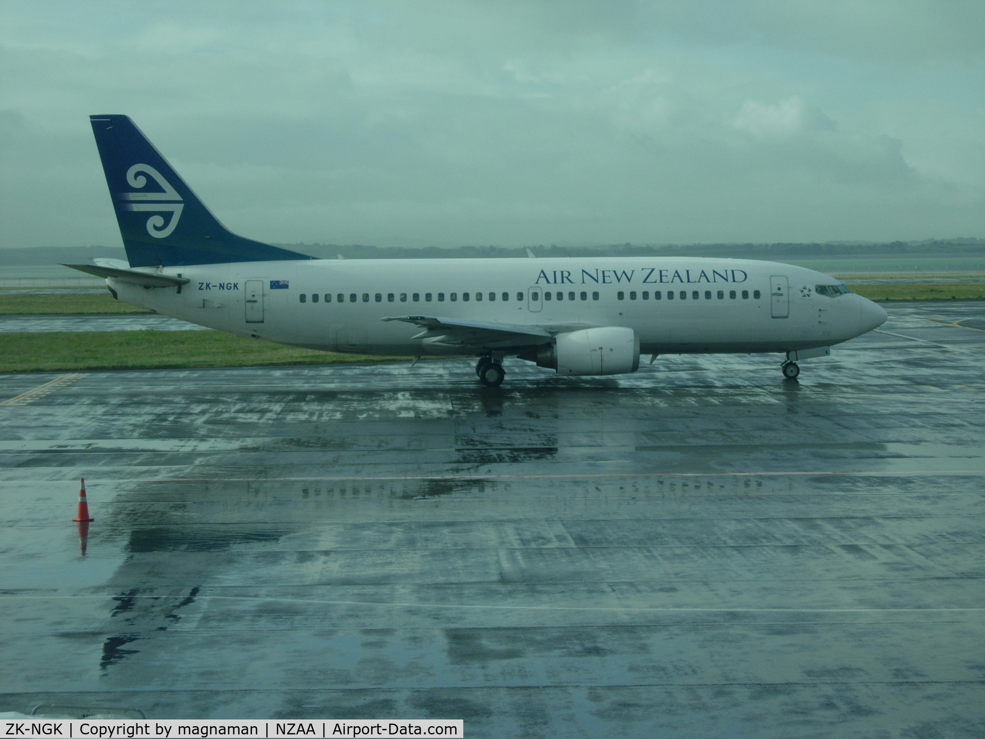 ZK-NGK, 1995 Boeing 737-3K2 C/N 26318, From a wet AKL airport - view from domestic baggage collection window.