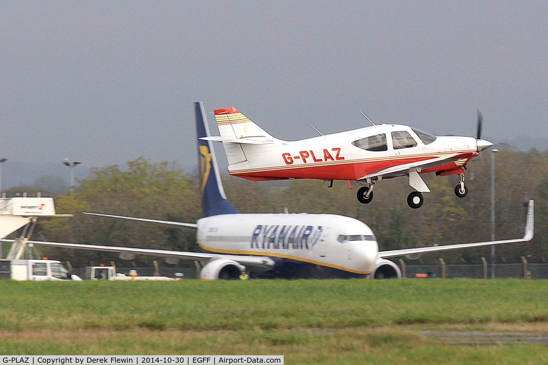 G-PLAZ, 1975 Rockwell International 112 Commander C/N 345, EGFF Resident Commander, previously N1345J, ZS-JRX, G-BFWG, G-RDCI, seen departing runway 12 for a local flight, EI-EBS seen taxxing below it.