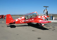 N772TA @ KIC - Strapping-in to brightly painted (Team) ORACLE 2006 Extra Flugzeugbau Gmbh EA 300/L @ Mesa del Rey (King City) Airport, CA - by Steve Nation