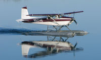 N5214E @ LHD - A beautiful mirror image as this Cessna 180B makes an early morning departure from Lake Hood - by Terry Fletcher