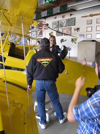 N1017U @ SZP - 1939 Bucker JUNGMANN C.A.S.A. 1.131, Lycoming O-360 180 Hp upgrade conversion, Pat Quinn demonstrating the rear cockpit to visitor to his Aviation Museum of Santa Paula hangar. Fine jacket! She won't need her purse there. - by Doug Robertson