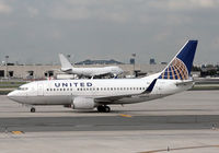 N24633 @ KEWR - A United Boeing 737-524 (built 1995) taxies past Newark's terminal C, while a 747 in the background maintains an air of indifference. - by Daniel L. Berek