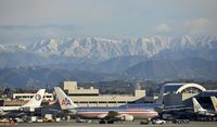 N332AA @ KLAX - Taxiing to gate under snow capped mountains - by Todd Royer
