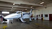 N122CR @ KHWD - Christopher Ranch LLC (Gilroy, CA) 2013 Embraer Phenom 100 sitting inside the Mather hangar for maintenance at Hayward Executive Airport, Hayward, CA. Apparently it's de-icing boots (located on the wing) blew up mid-flight. - by Chris Leipelt