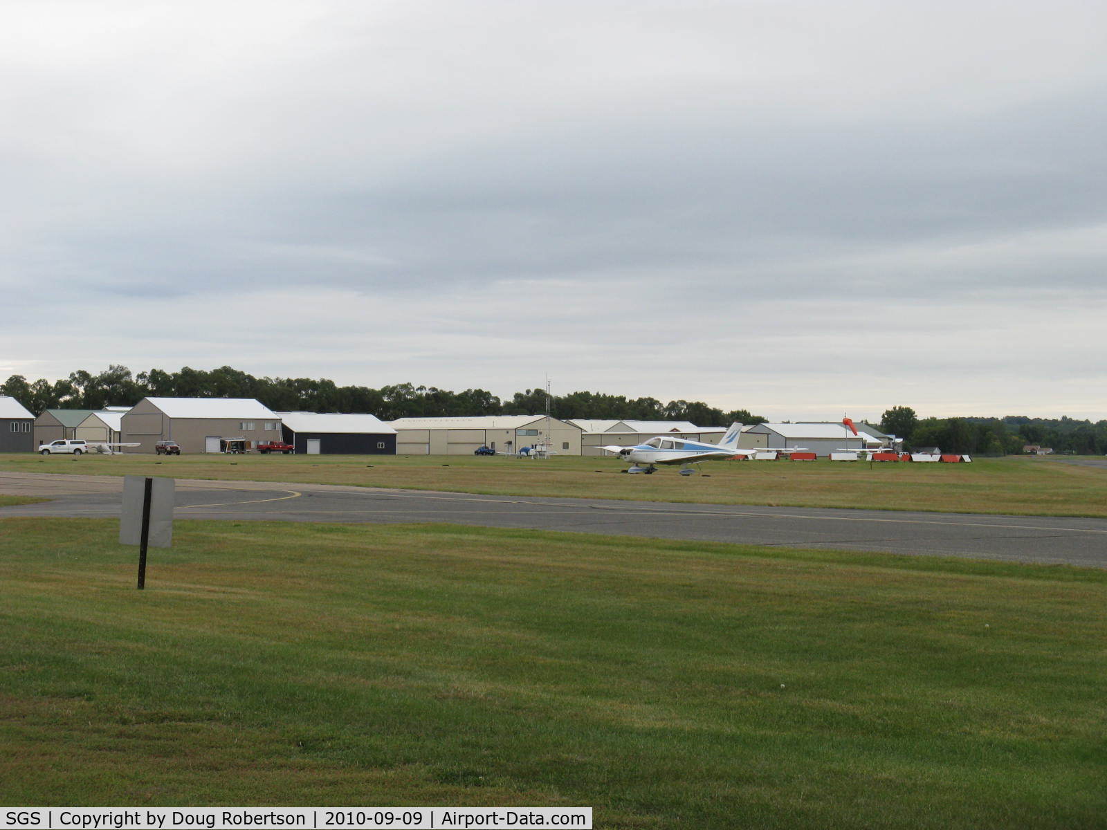 South St Paul Muni-richard E Fleming Fld Airport (SGS) - Aircraft hangars, windsock, taxiway in foreground