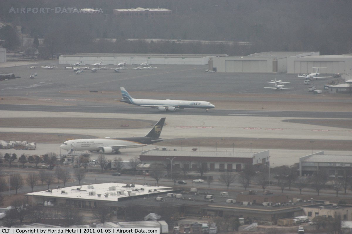 Charlotte/douglas International Airport (CLT) - Not top quality - it is cloudy and hazy, we are moving and the windows were scratched on my plane N744P (US A319 Piedmont colors).  ATI DC-8 lands on parallel runway, UPS 767 in foreground and large GA ramp in background