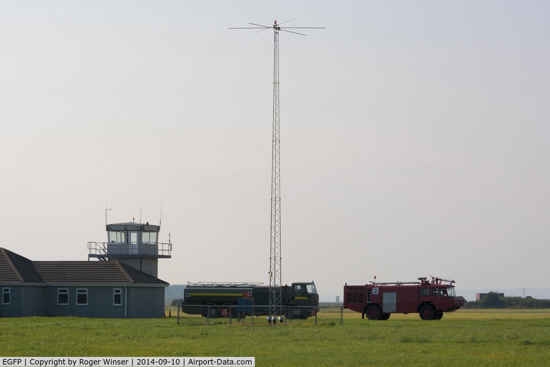 Pembrey Airport, Pembrey, Wales United Kingdom (EGFP) - Control Tower, fuel tender, radio mast and the airport Fire and Rescue tender #2. In the distance (between the two vehicles) can be see an observation tower on the adjacent DIO Pembrey Sands Air Weapons Range (EGOP). 