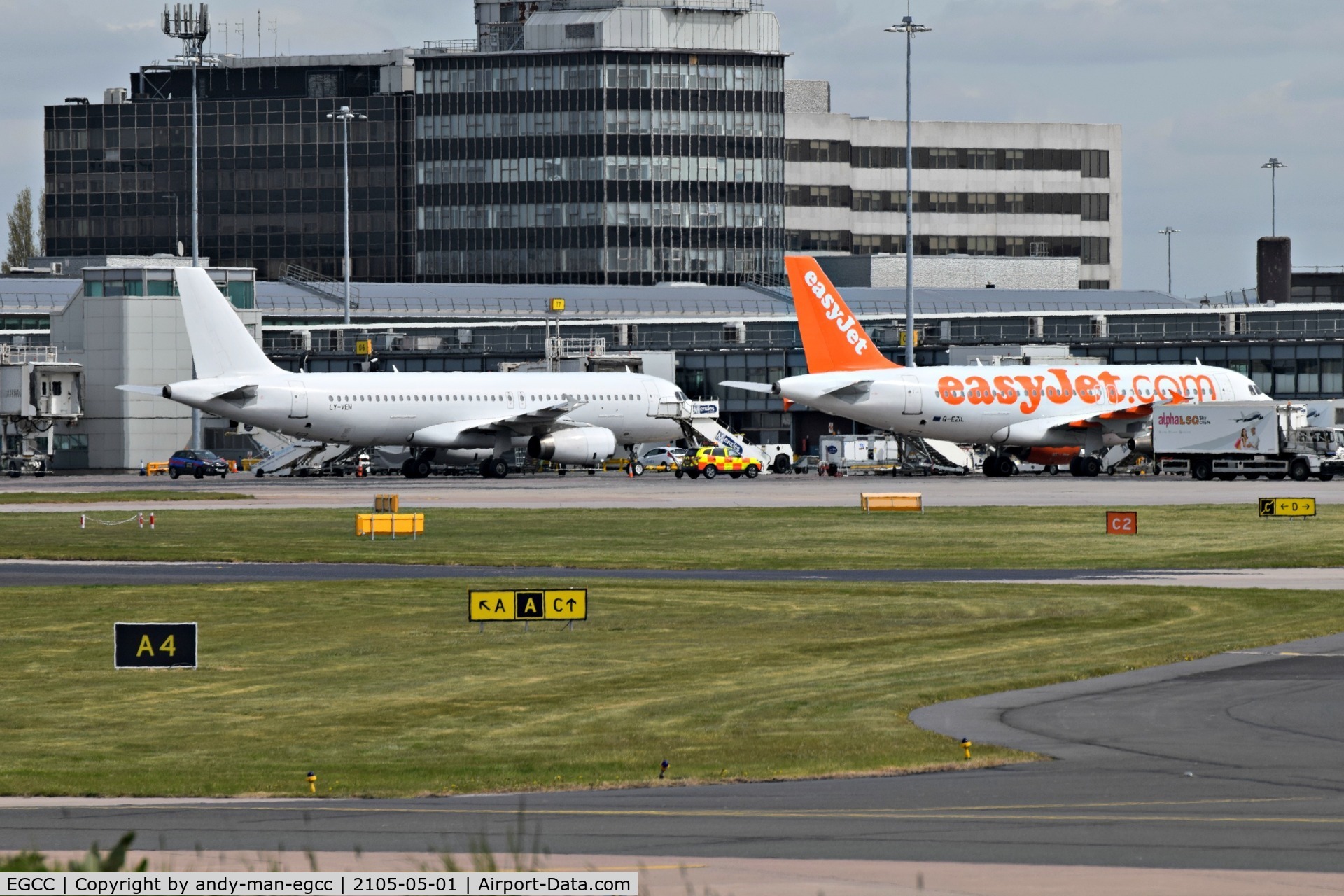 Manchester Airport, Manchester, England United Kingdom (EGCC) - on the left is LY-VEN A320 parked on its stand/gate and on the right is G-EZIL A319 EZY parked on its stand/gate