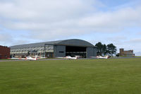 RAF Syerston - Overview of the Air Cadets flightline. The old 1939 built J-type hangar is still in use, but the watchtower to the right is now replaced by a mobile caravan. - by Joop de Groot