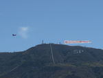 Santa Paula Airport (SZP) - N65124 Boeing Stearman towing FOLLOW THE BACON-Carl's Jr. advertising banner past South Mountain, viewable by all of Santa Paula, CA. - by Doug Robertson